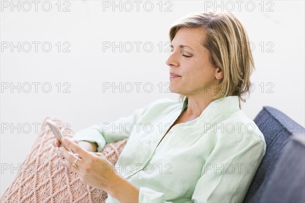 Woman using smart phone on sofa