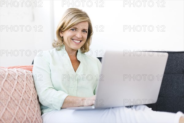 Woman holding laptop on sofa