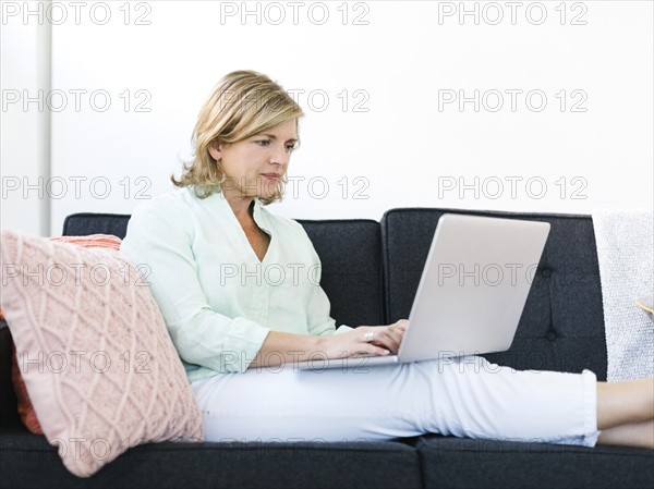 Woman sitting on sofa and using laptop