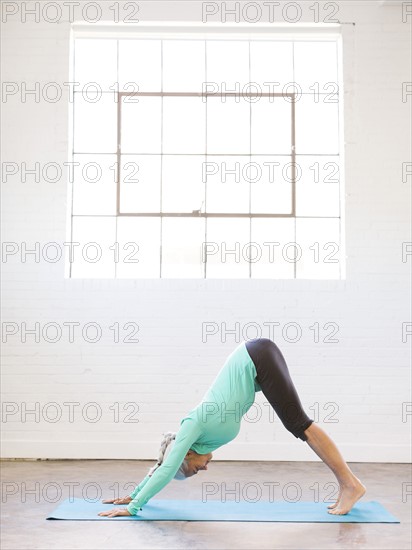 Senior woman practicing yoga on mat