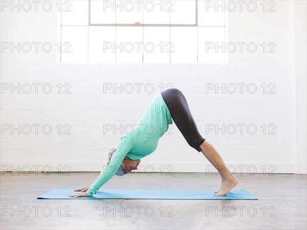 Senior woman practicing yoga on mat