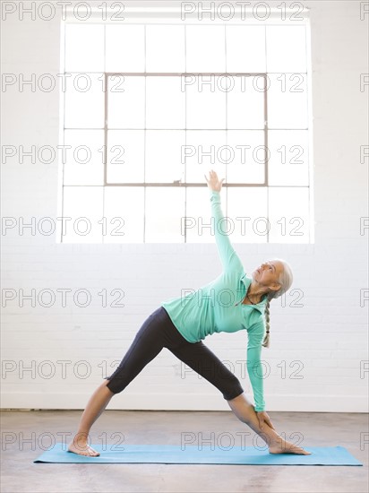 Senior woman practicing yoga on mat