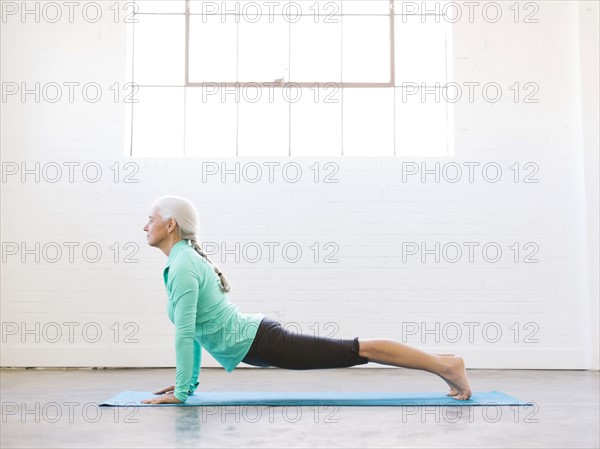 Senior woman practicing yoga on mat