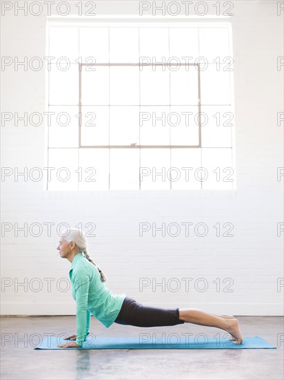 Senior woman practicing yoga on mat