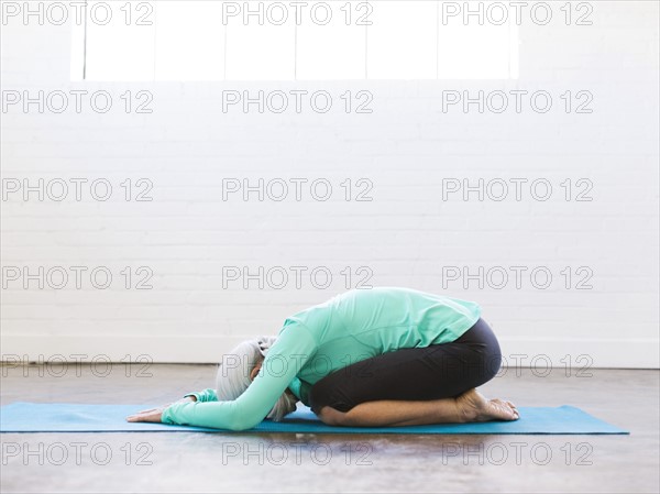 Senior woman practicing yoga on mat