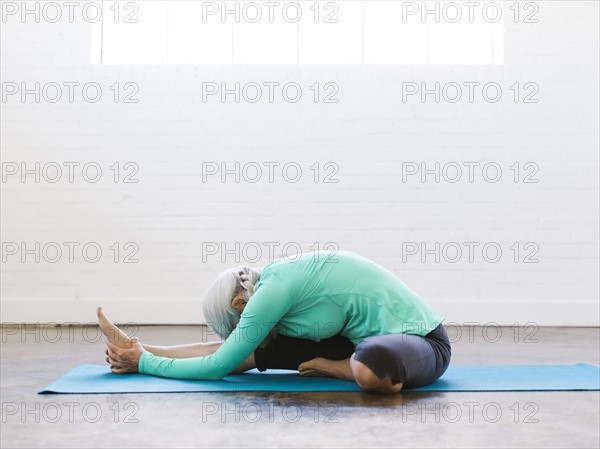 Senior woman practicing yoga on mat