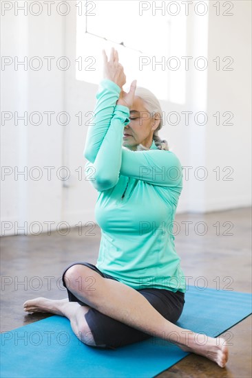 Senior woman practicing yoga on mat