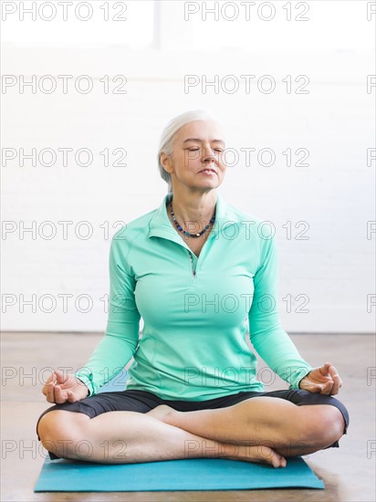 Senior woman meditating on mat