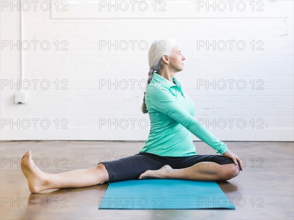 Senior woman practicing yoga on mat