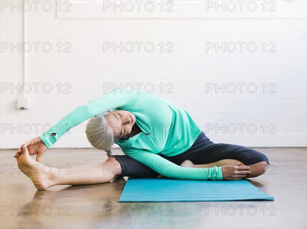 Senior woman practicing yoga on mat