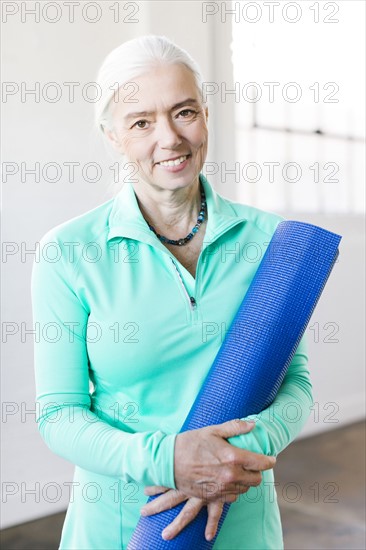 Portrait of senior woman holding mat