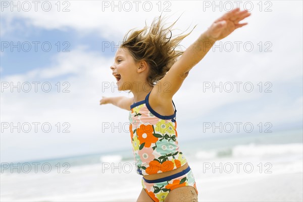 Girl (6-7) spinning on beach