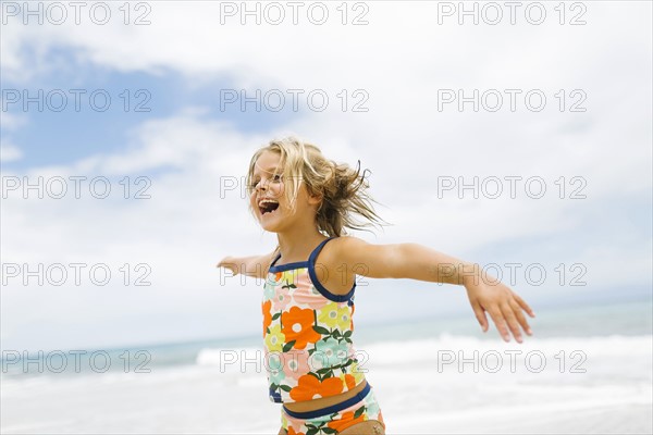 Girl (6-7) spinning on beach