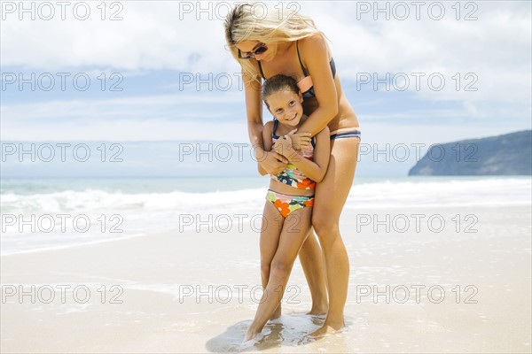 Mother and daughter (6-7) embracing on beach