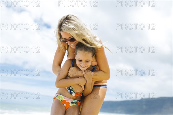 Mother and daughter (6-7) embracing on beach