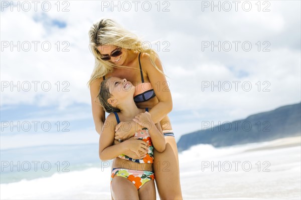 Mother and daughter (6-7) embracing on beach