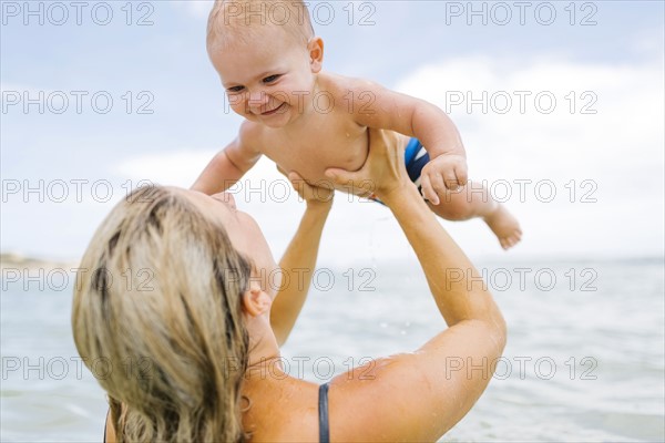 Mother playing with son (12-17 months) in sea