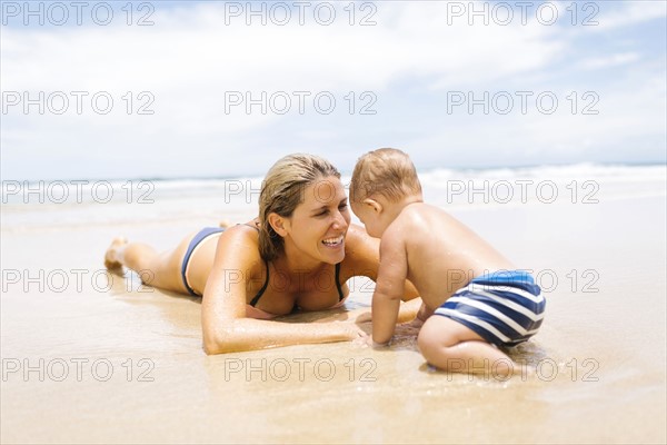 Mother playing with son (12-17 months) on beach