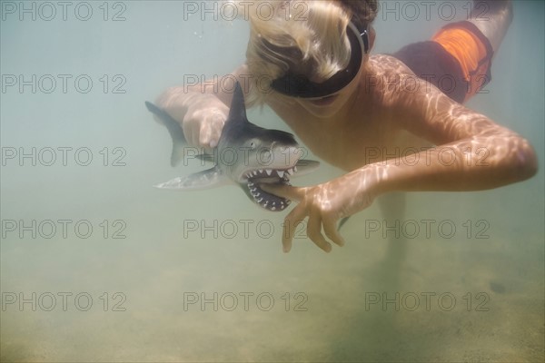 Boy (8-9) playing with toy shark in sea