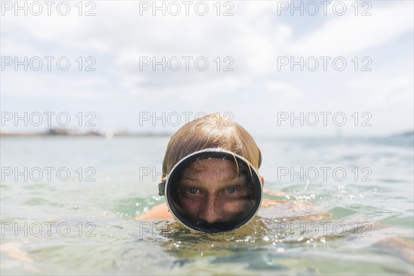 Man wearing swimming goggles swimming in sea
