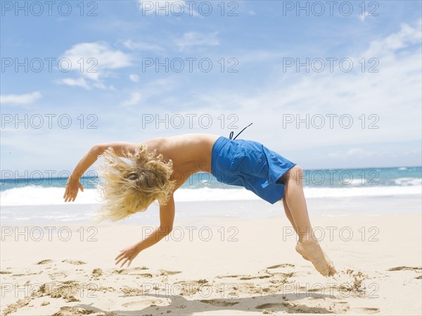 Boy (8-9) backfilling on beach
