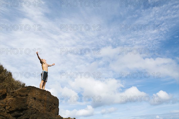 Man standing on rock against blue sky