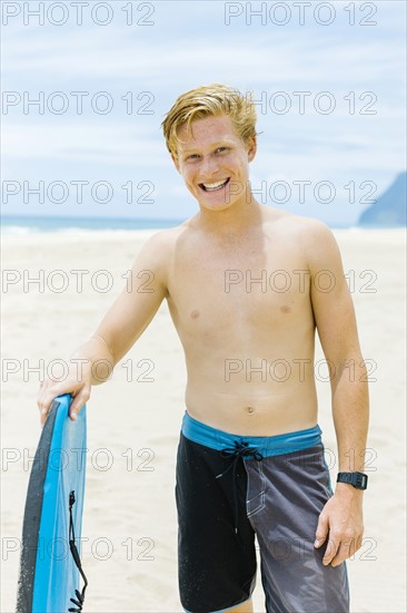 Man standing on beach and holding surfboard