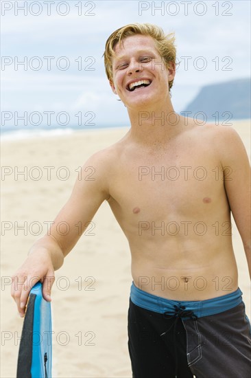 Man standing on beach and holding surfboard