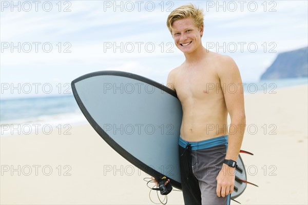 Man standing on beach and holding surfboard