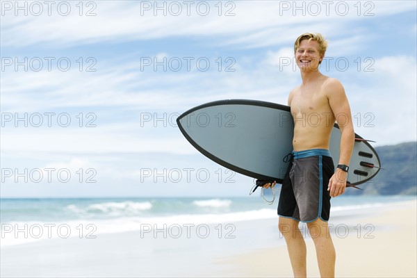 Man standing on beach and holding surfboard