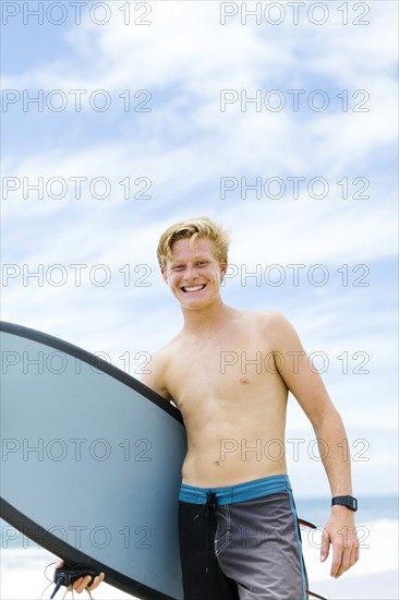 Man standing on beach and holding surfboard