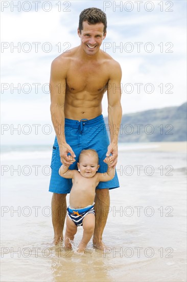 Son (12-17 months) learning to walk with father on beach