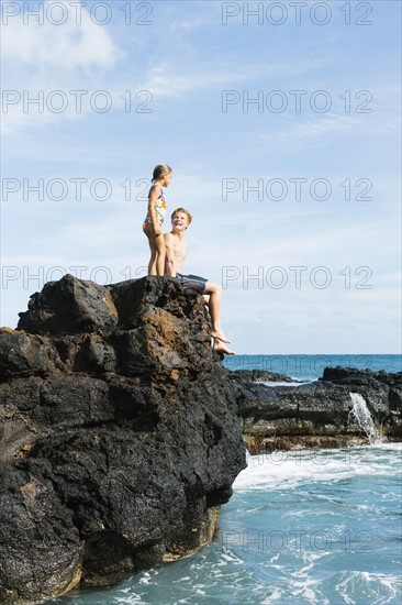 Man and girl (6-7) resting on cliff