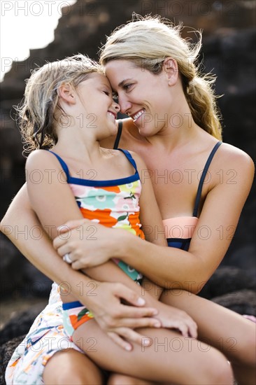 Mother and daughter (6-7) embracing with rock in background