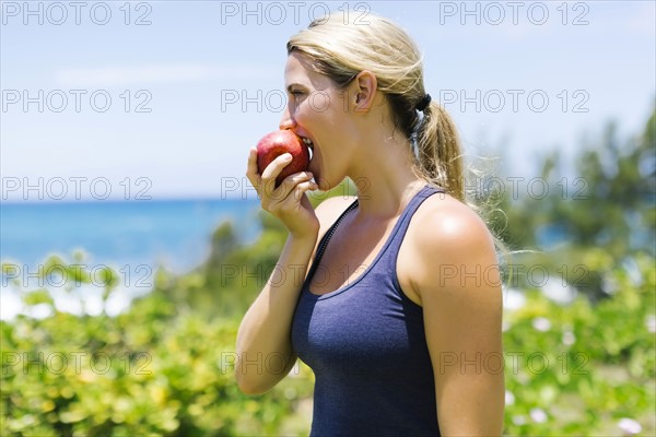 Blonde beautiful woman eating fresh apple