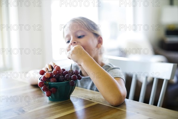 Young girl (6-7) eating fresh grapes