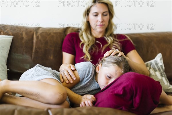 Woman sitting with daughter (6-7) on couch