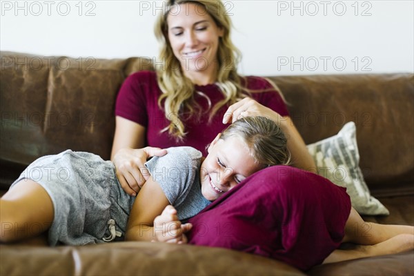 Woman sitting with daughter (6-7) on couch