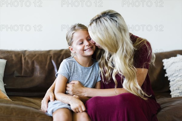 Woman giving daughter (6-7) cheek kiss