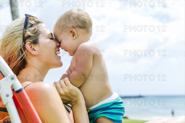 Woman sitting on deck chair with little son (18-23 months)