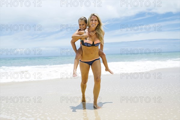 Daughter (6-7) playing with mother on beach at sunny day