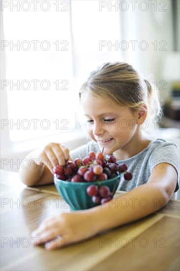 Young girl (6-7) eating fresh grapes