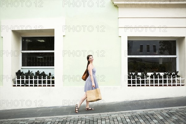Puerto Rico, San Juan, Woman with shopping bag walking city streets