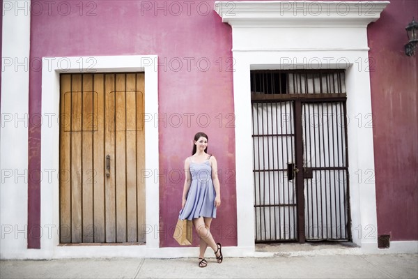 Puerto Rico, San Juan, Woman with shopping bag standing in front of pink building