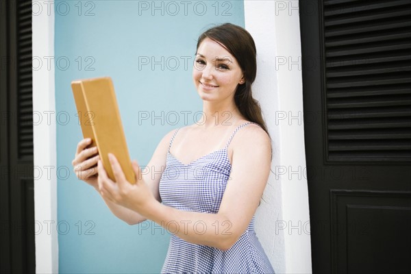 Woman with tablet doing selfie on city street