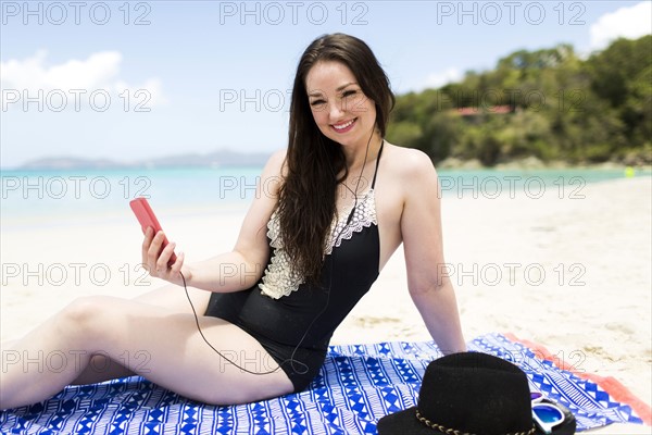 USA, Virgin Islands, Saint Thomas, Woman listening to music on beach during summer vacations