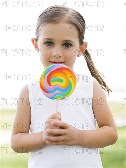 Girl (4-5) holding colorful lollipop