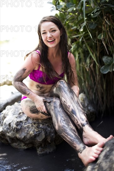 Sitting woman with legs covered with mud