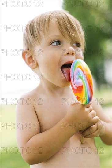 Boy (2-3) licking lollipop
