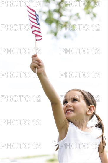 Smiling girl (4-5) holding american flag